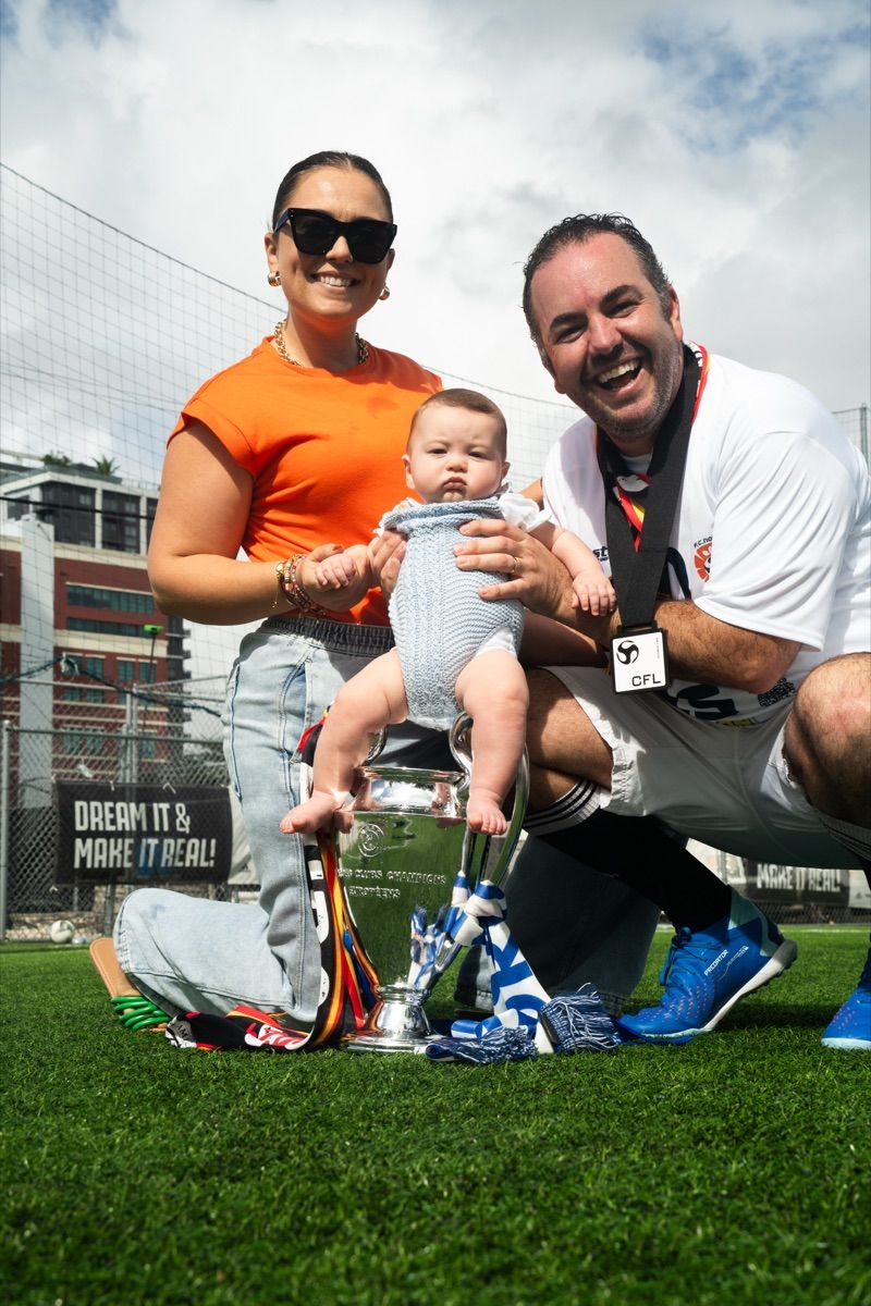 Family holding their baby on the trophy under the Dream It and Make It Real banner
